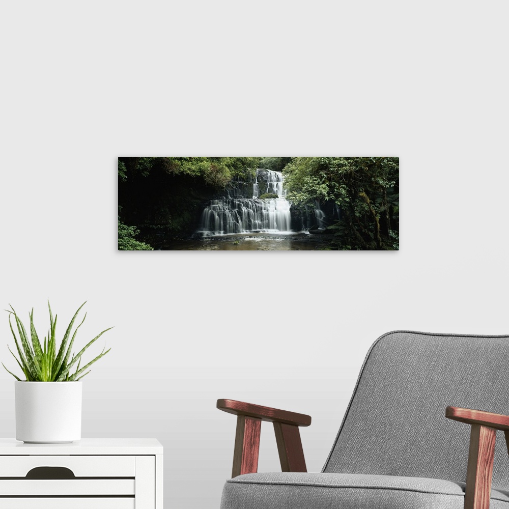 A modern room featuring Wide angle photograph of green trees and foliage surrounding Purakaunui Falls in the Catlins, on ...