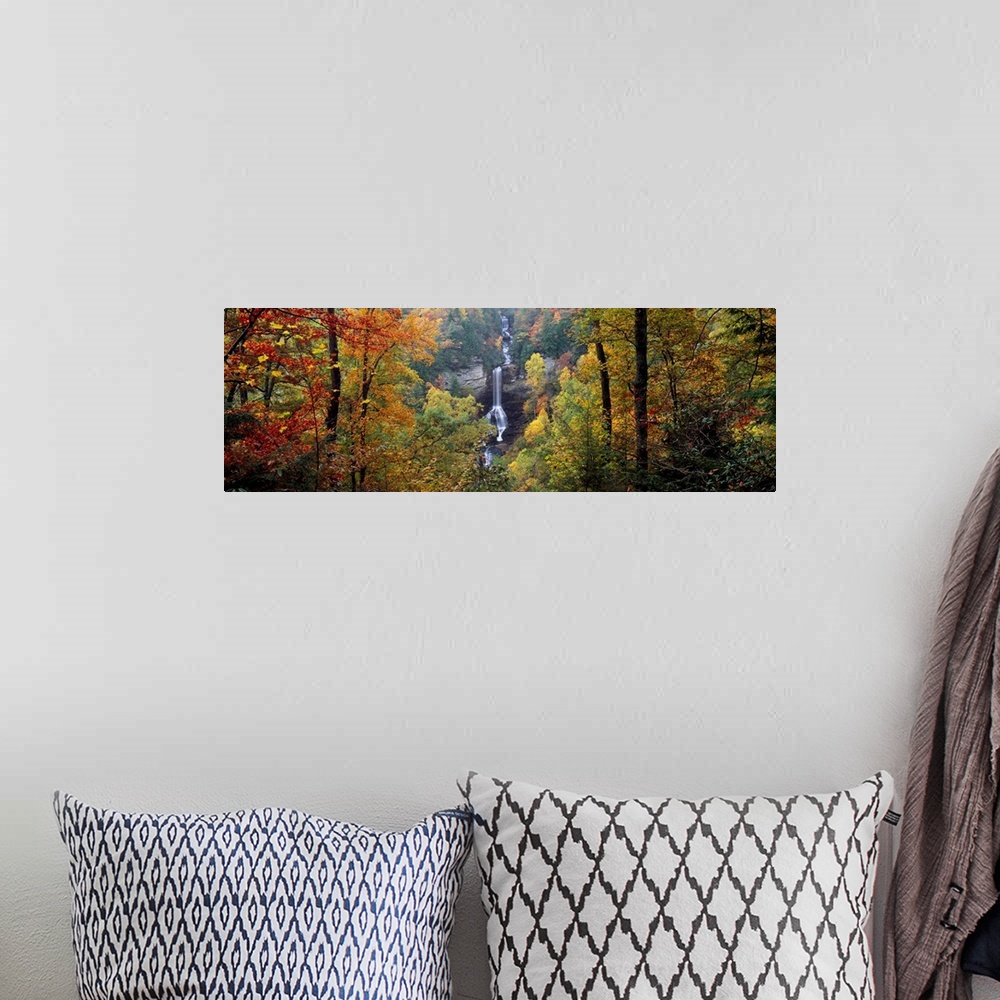 A bohemian room featuring This panoramic wall art is a photograph of a waterfall cascading down a sheet rock face in an aut...