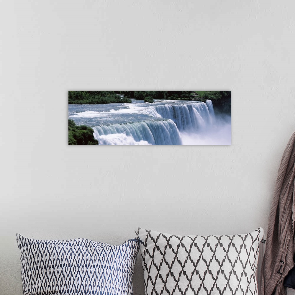 A bohemian room featuring A large panoramic photograph taken of Niagara falls with trees and foliage lining the back of the...
