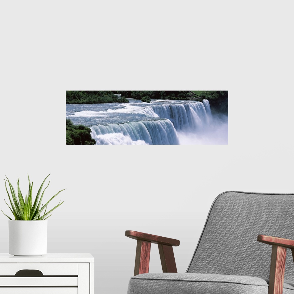 A modern room featuring A large panoramic photograph taken of Niagara falls with trees and foliage lining the back of the...