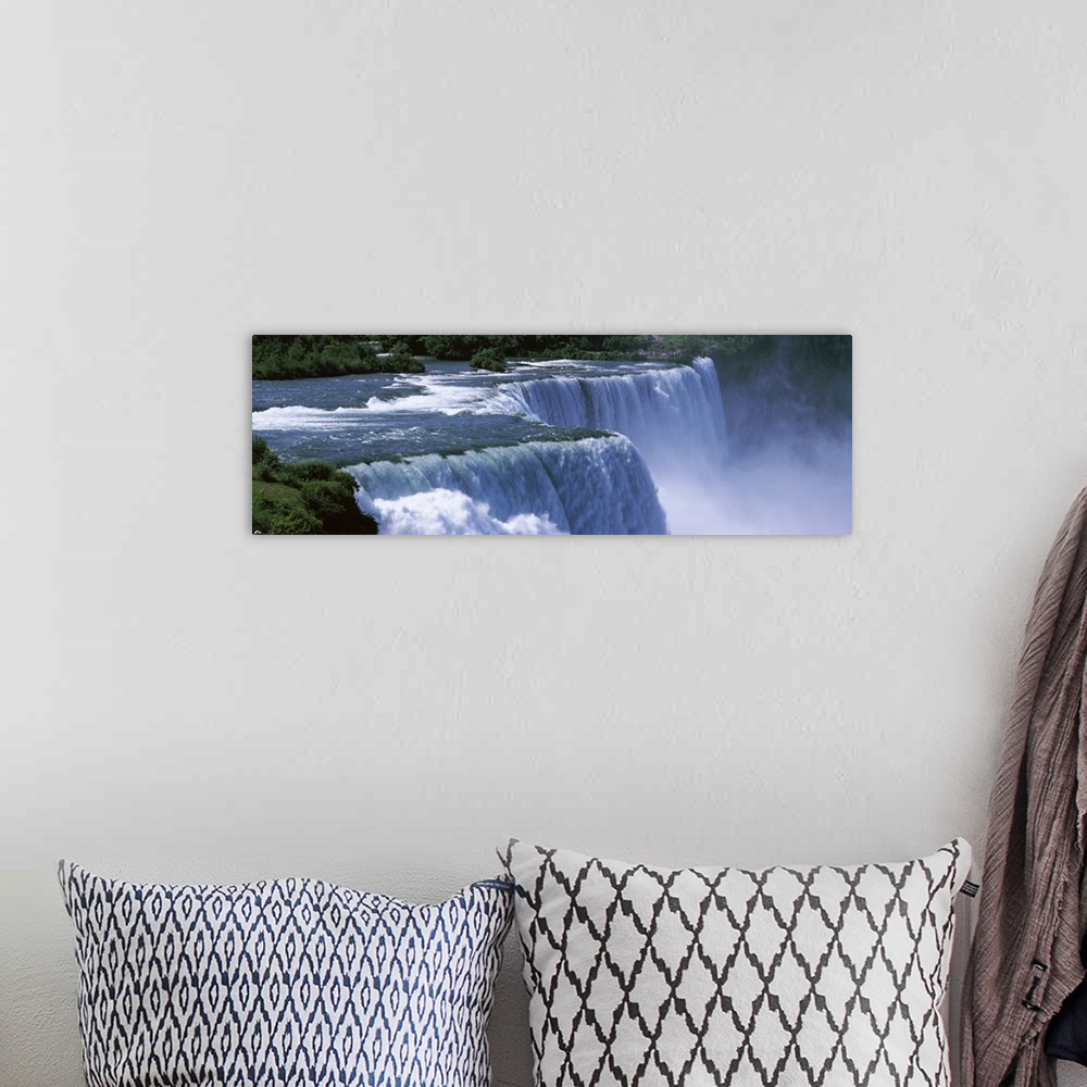 A bohemian room featuring Panoramic photo of a water rushing over a waterfall with mist coming up from the bottom.