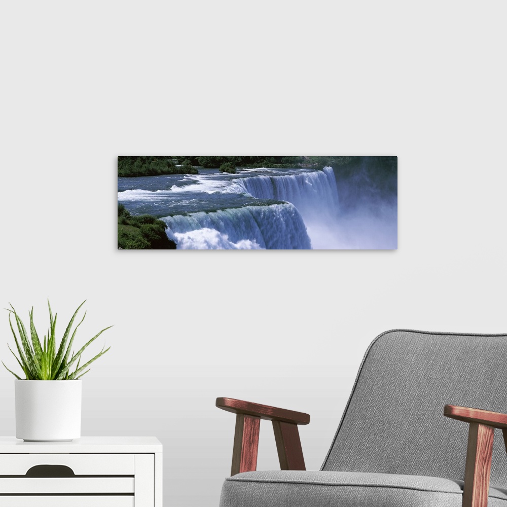 A modern room featuring Panoramic photo of a water rushing over a waterfall with mist coming up from the bottom.