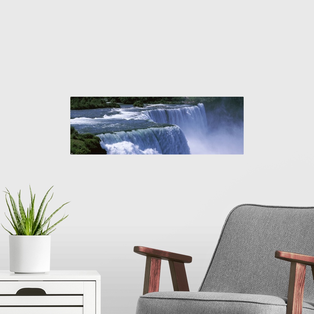 A modern room featuring Panoramic photo of a water rushing over a waterfall with mist coming up from the bottom.