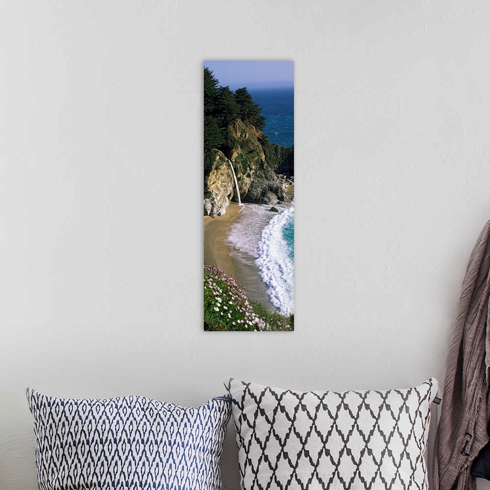 A bohemian room featuring Vertical panoramic photo of a small waterfall in the rocky cliffs of the Pacific coast at low tide.