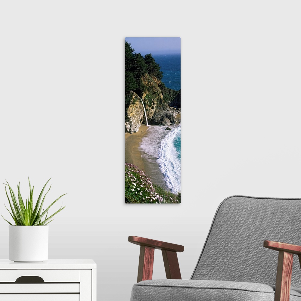 A modern room featuring Vertical panoramic photo of a small waterfall in the rocky cliffs of the Pacific coast at low tide.