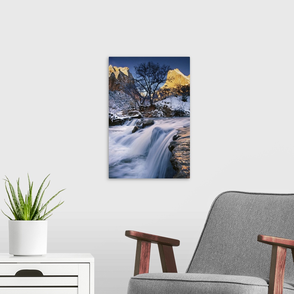A modern room featuring Water rushing over a rocky riverbed in a snowy landscape under bare trees in a valley in Zion Nat...