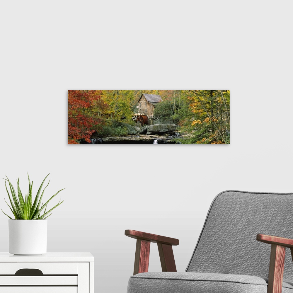 A modern room featuring Panoramic photograph of mill in forest surrounded by fall foliage.