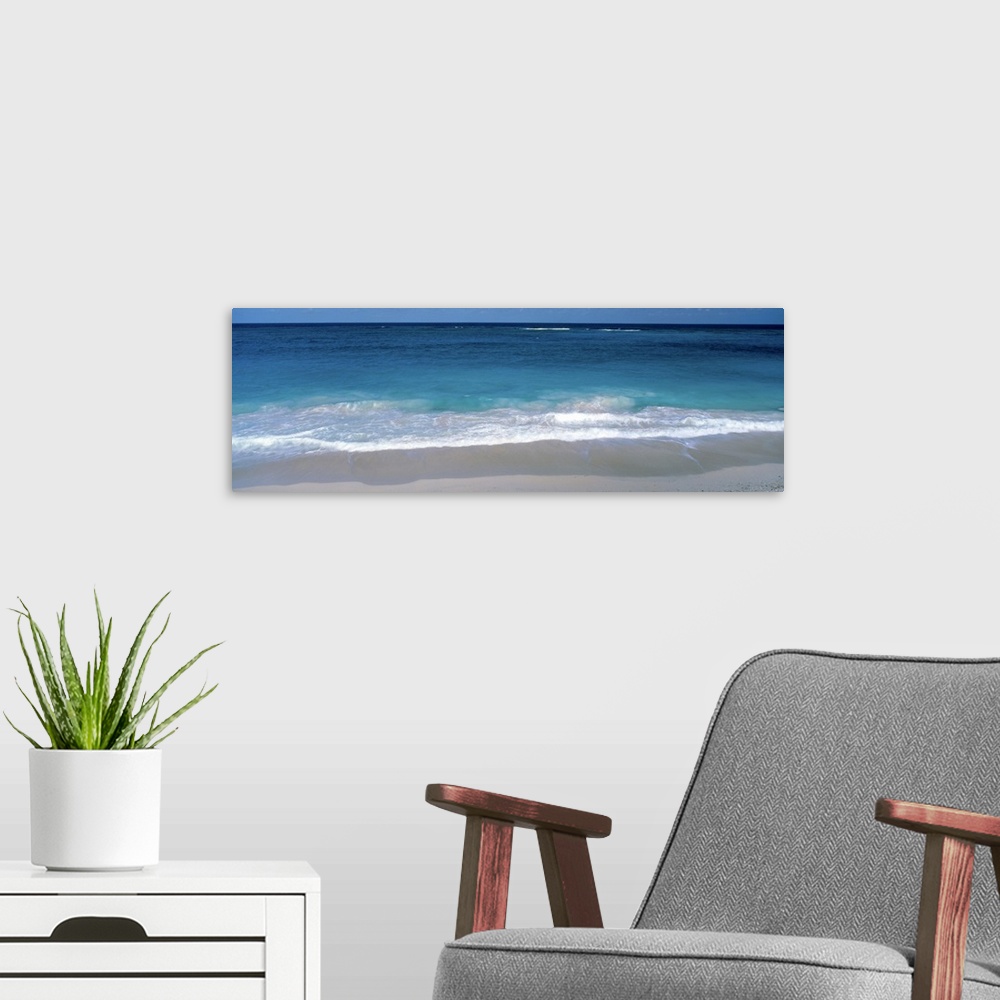 A modern room featuring Panoramic picture of waves coming up on the white sandy beach in the Caribbean.