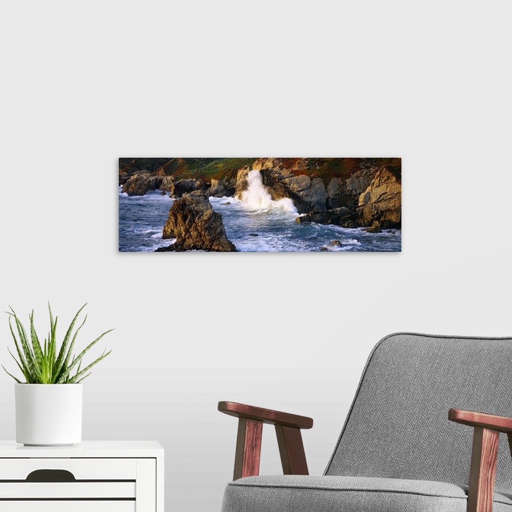 A modern room featuring Horizontal photo print of waves crashing into rocky cliffs in the Pacific Ocean and rock formatio...
