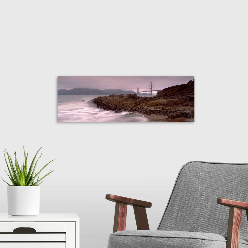 A modern room featuring Panoramic photograph shows waves breaking against the rocky shores of Baker Beach in San Francisc...