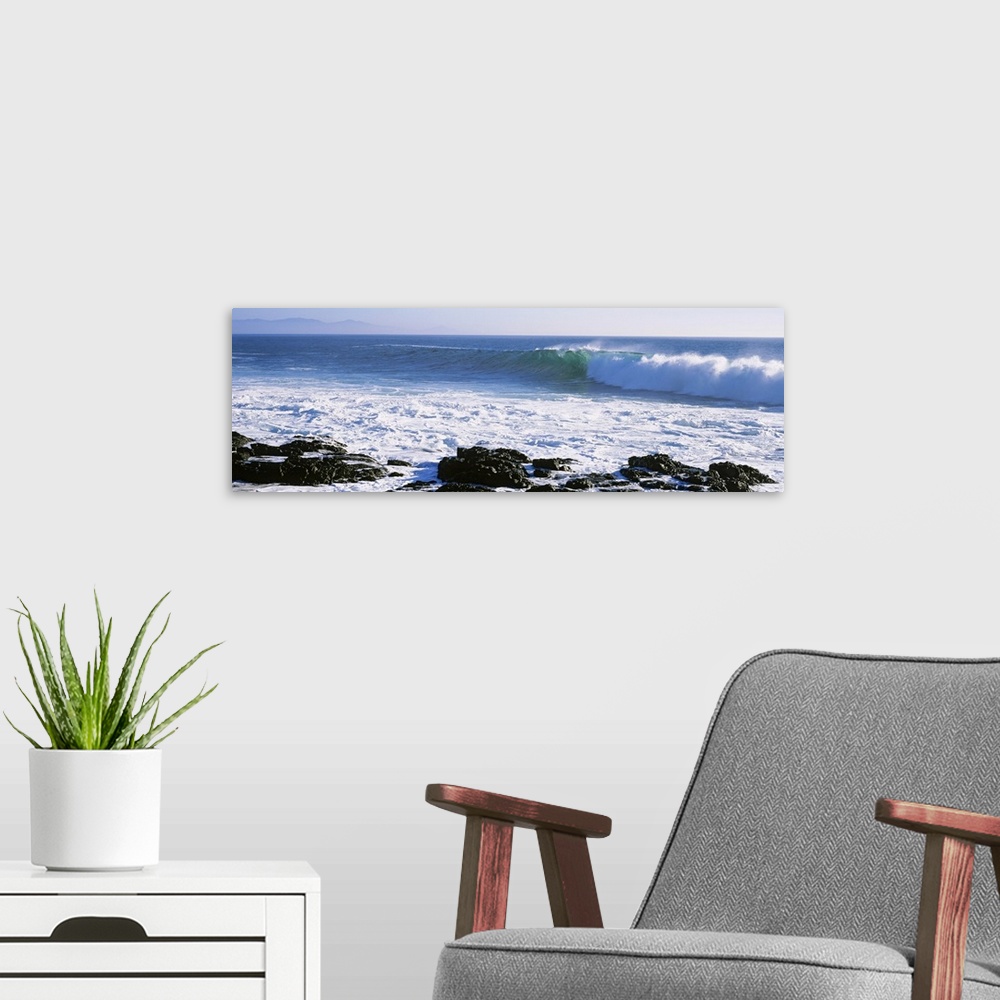 A modern room featuring Long image on canvas of big waves crashing onto a rocky shore.