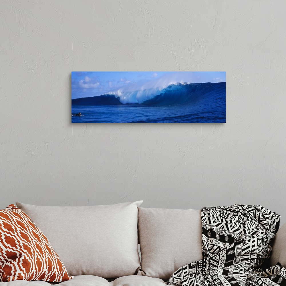 A bohemian room featuring This panoramic photograph captures a curling wave collapses on itself while a surfer paddles out ...