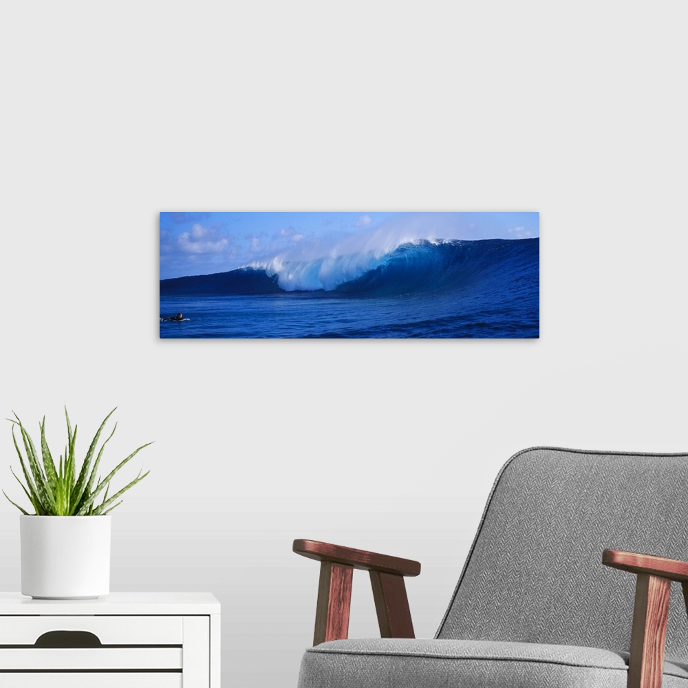 A modern room featuring This panoramic photograph captures a curling wave collapses on itself while a surfer paddles out ...
