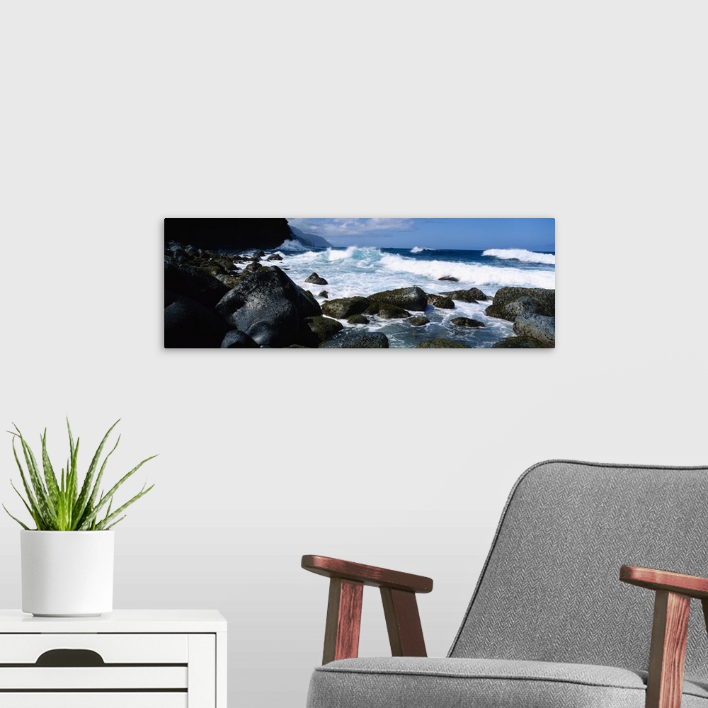 A modern room featuring Panoramic photograph on a big canvas of waves crashing onto large rocks along the coast of Na Pal...