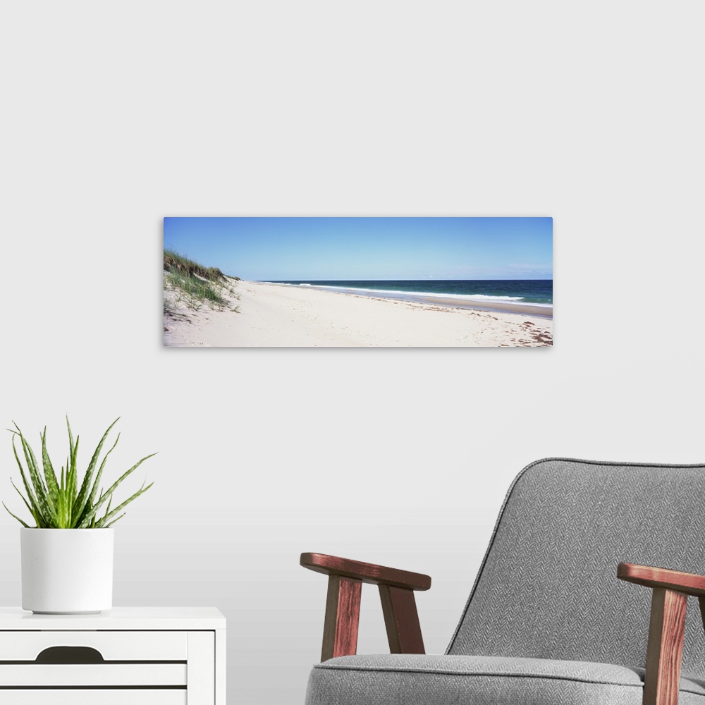 A modern room featuring Panoramic photograph taken of the beach with the sand dunes just to the left and the ocean water ...