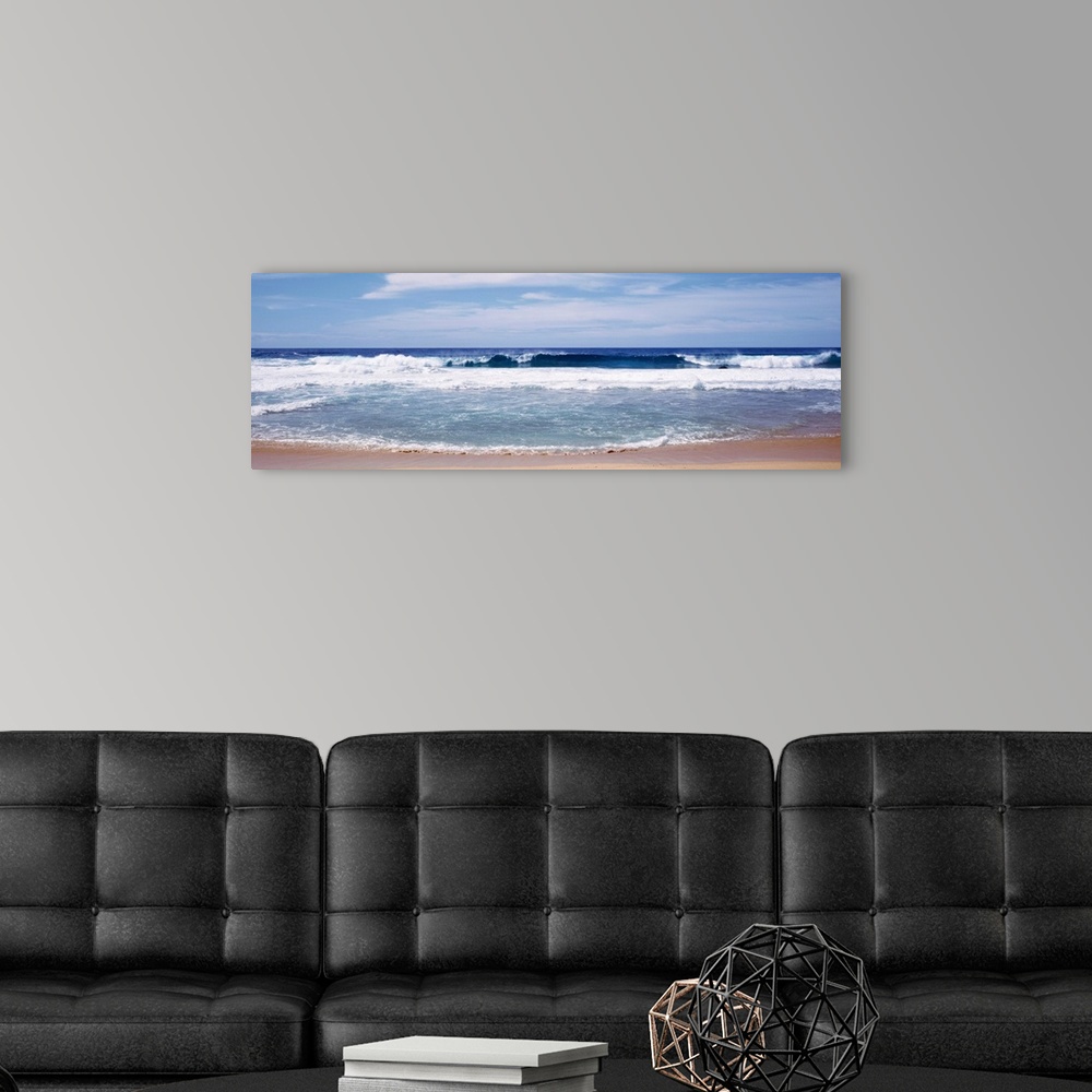 A modern room featuring Panoramic photograph displays the waves of an ocean aggressively crashing into a sandy beach on a...