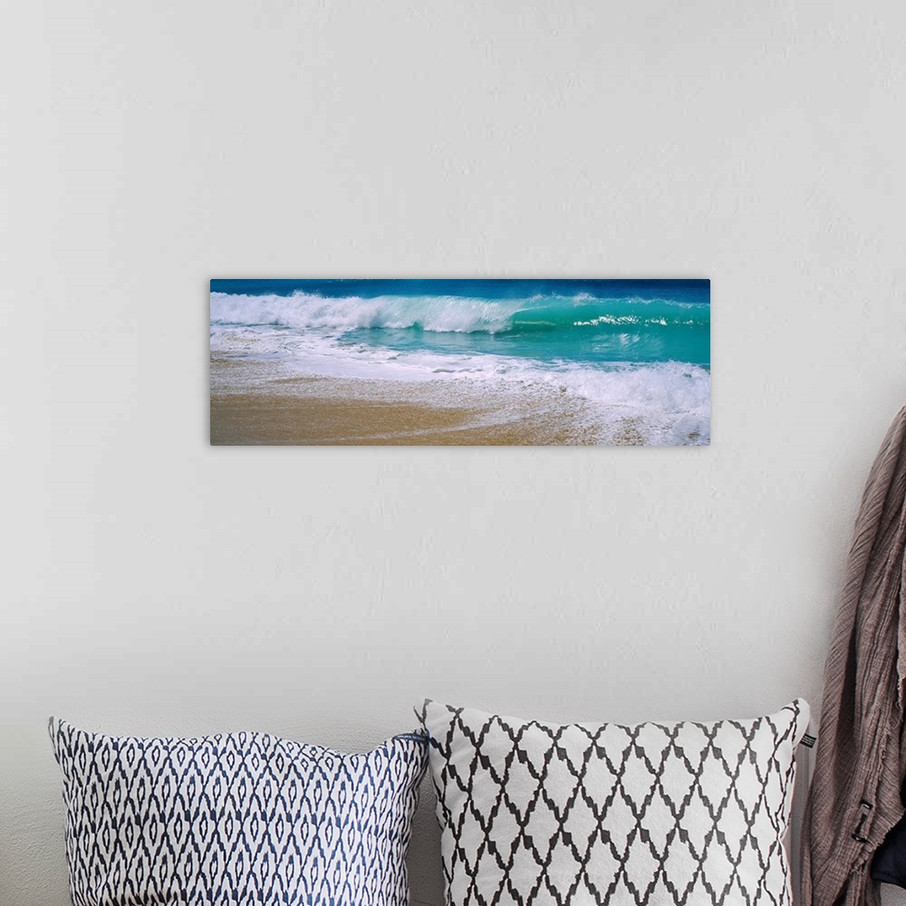 A bohemian room featuring Panoramic photograph of water crashing onto the sand and being swept back out to sea.