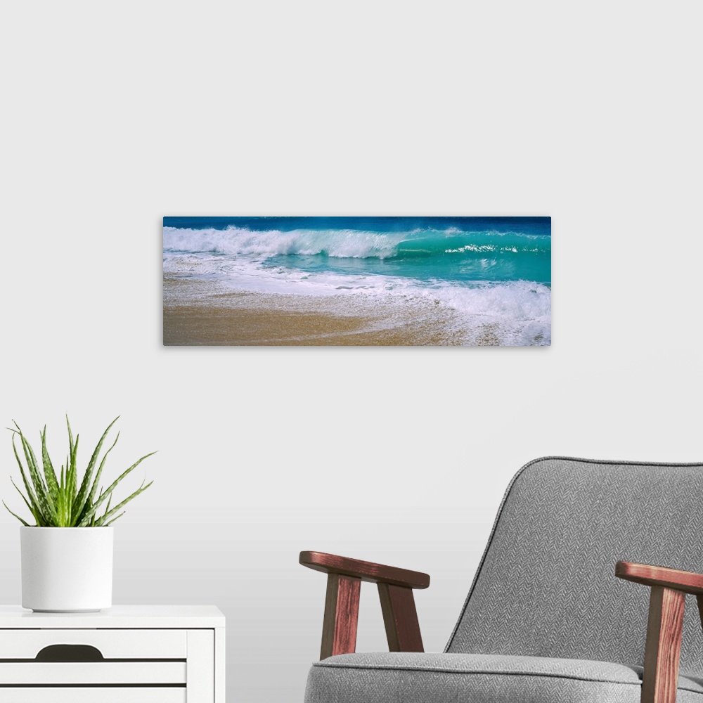 A modern room featuring Panoramic photograph of water crashing onto the sand and being swept back out to sea.