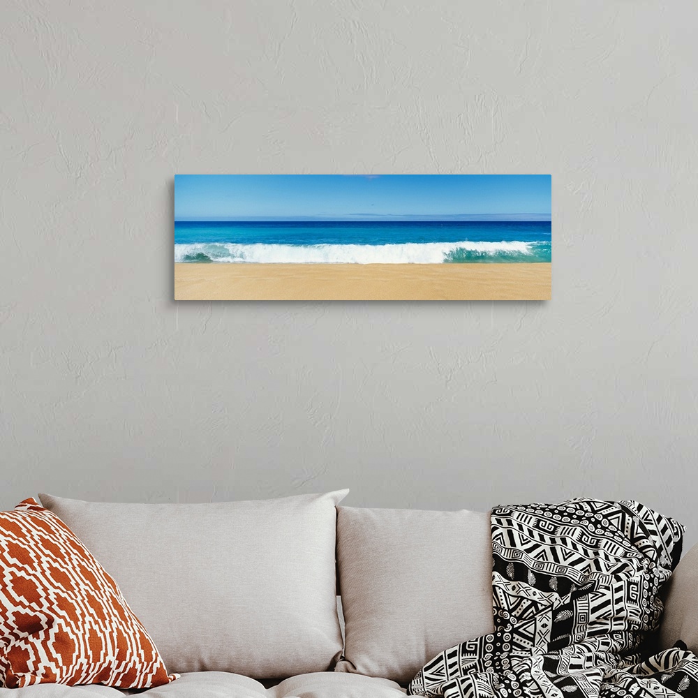 A bohemian room featuring This panoramic photograph captures a swell breaking on the sandy shore of a tropical beach on a c...
