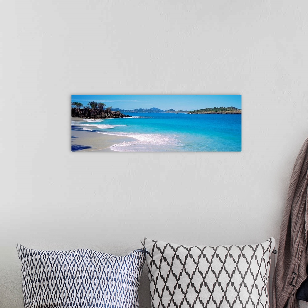 A bohemian room featuring Panoramic photograph displays the calm waters of this bay slowly crashing into the sandy beach, w...