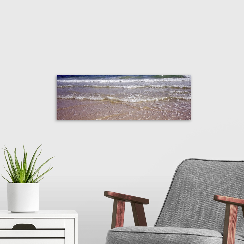 A modern room featuring Giant, landscape photograph of small waves rolling onto the shore, covering the sand, in the Gulf...