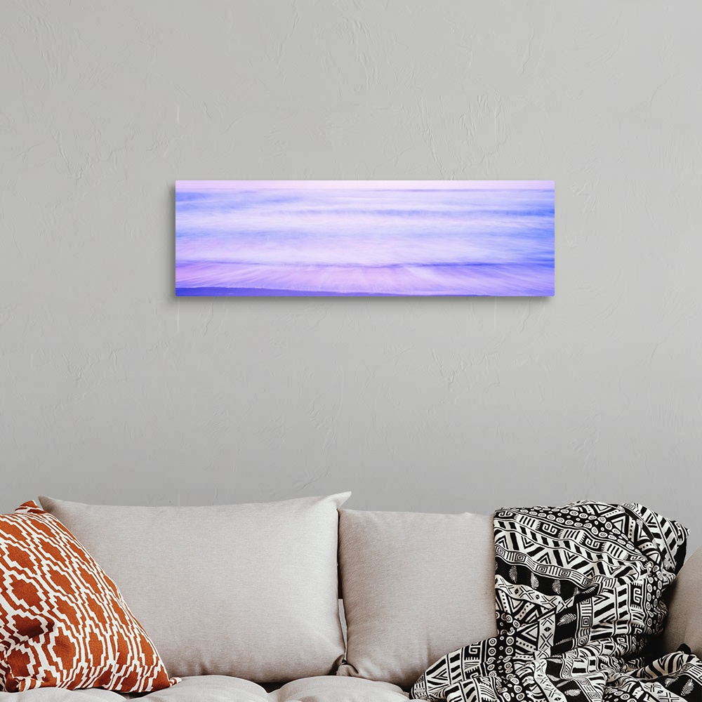 A bohemian room featuring A large panoramic picture taken of waves that are about to hit the beach with a dusk like sky abo...