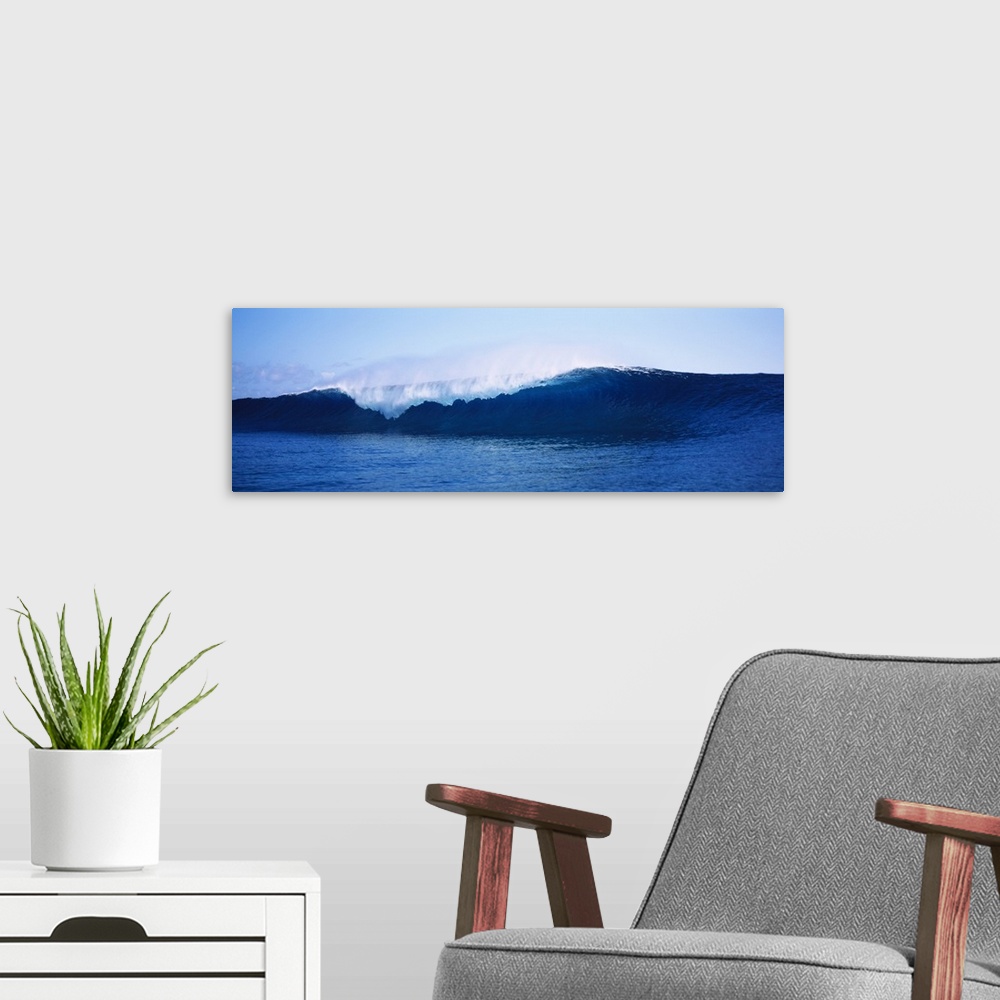 A modern room featuring Breaking wave about to crash in the sea with ocean spray flying off the crest under a clear blue ...
