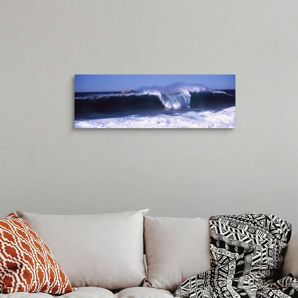 A bohemian room featuring This panoramic beach photograph captures a wave curling and breaking off the shore.