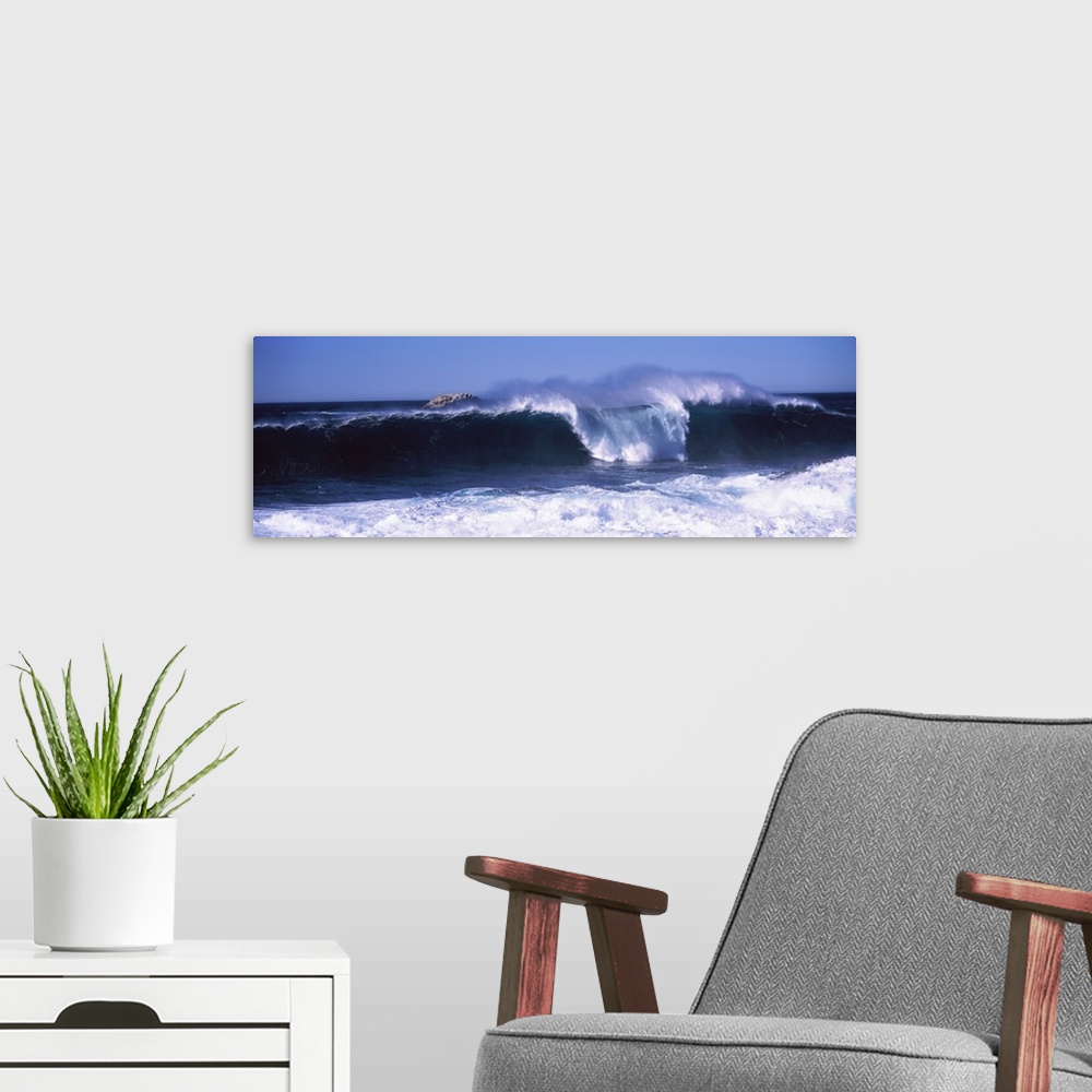 A modern room featuring This panoramic beach photograph captures a wave curling and breaking off the shore.