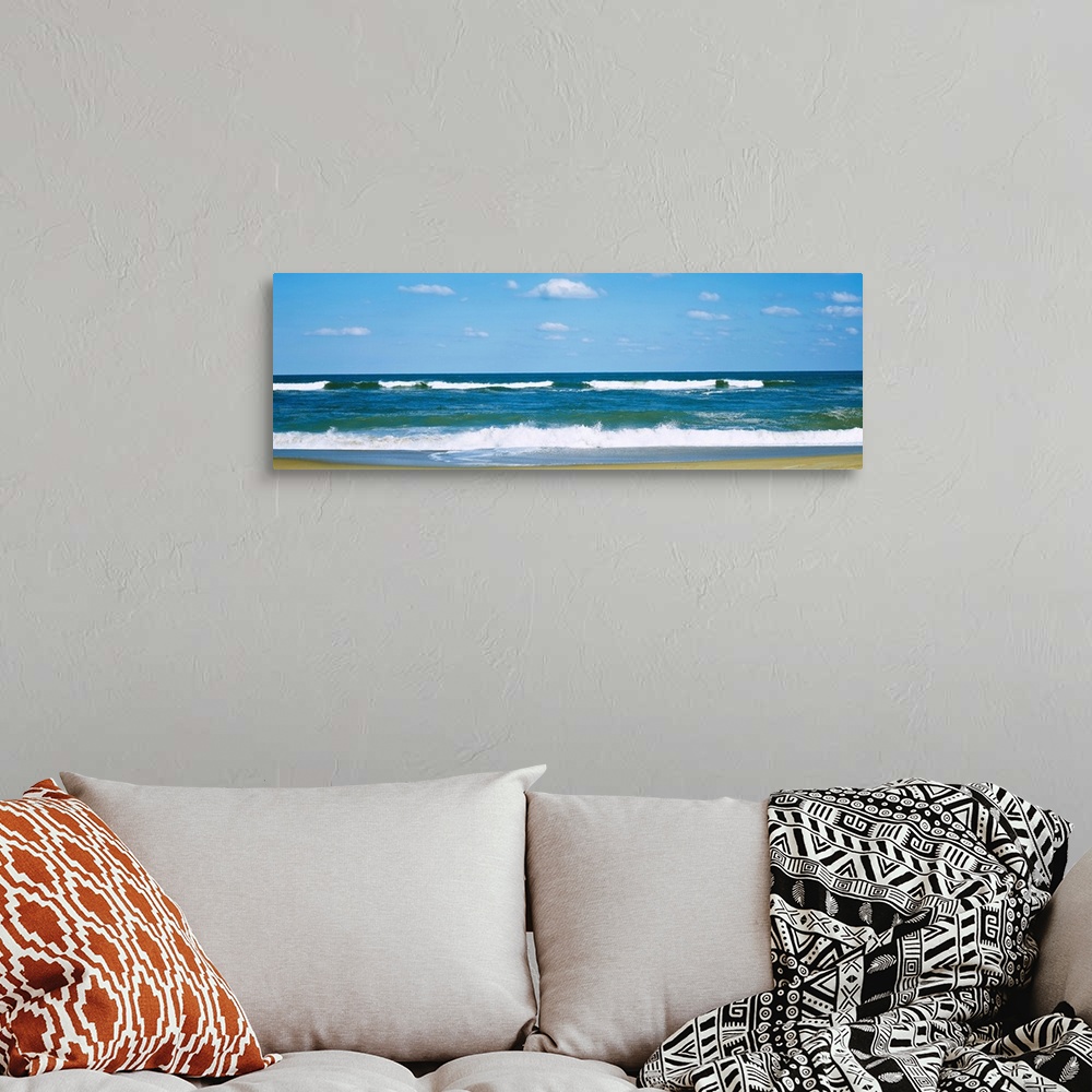 A bohemian room featuring Panoramic landscape photograph of a clear day at the beach with waves washing up on the sandy beach.