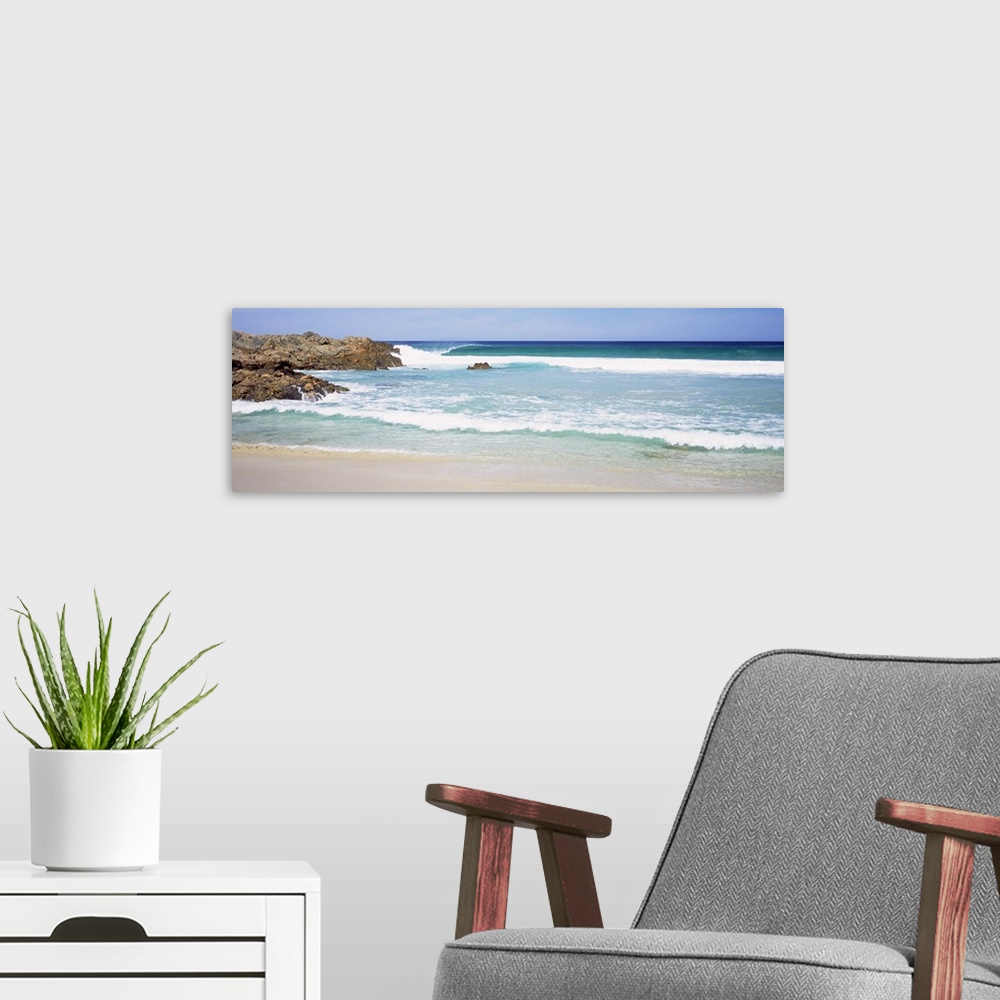 A modern room featuring Wide angle photograph of waves crashing into the beach, large rocks jutting into the waters in Au...