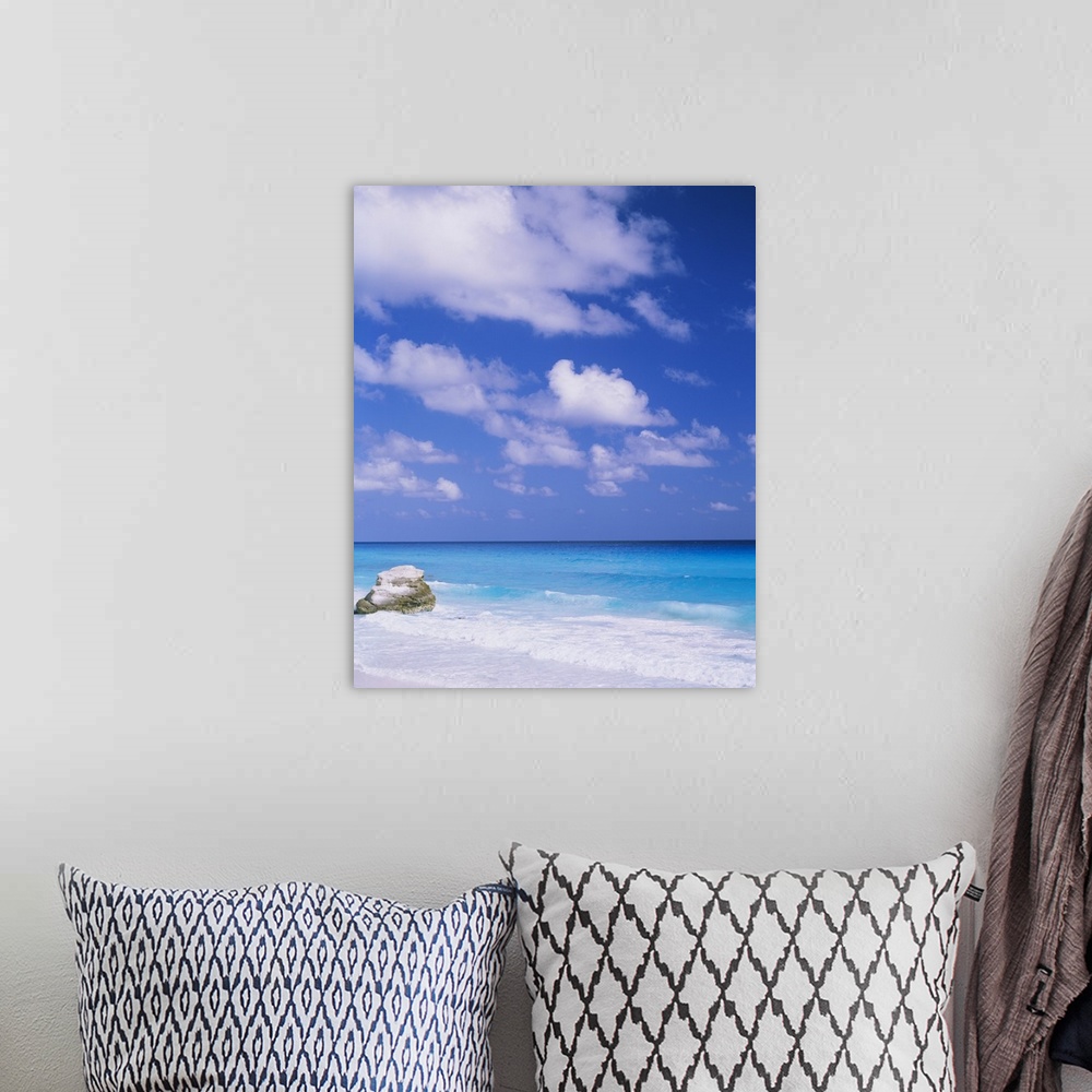A bohemian room featuring Large photograph displays a lone rock sitting on a beach, while the waves of a sea begin to crash...