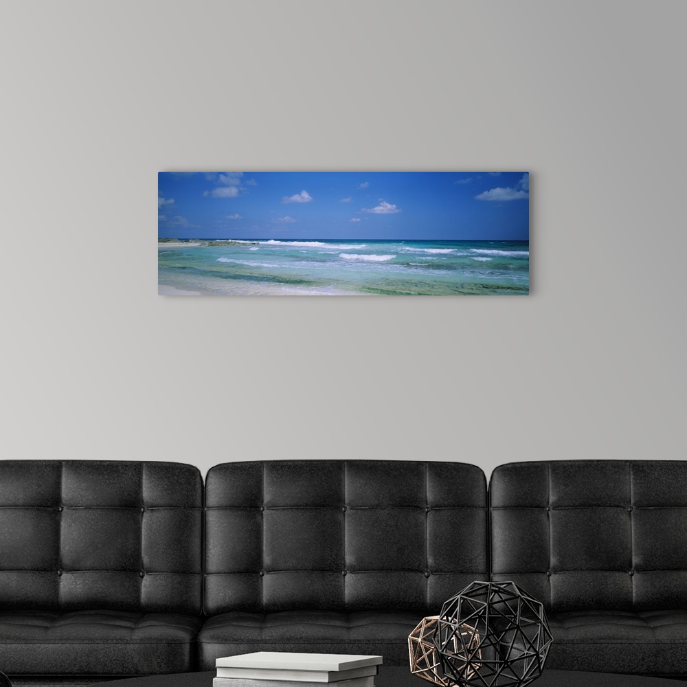 A modern room featuring Panoramic image of waves crashing on the beach.