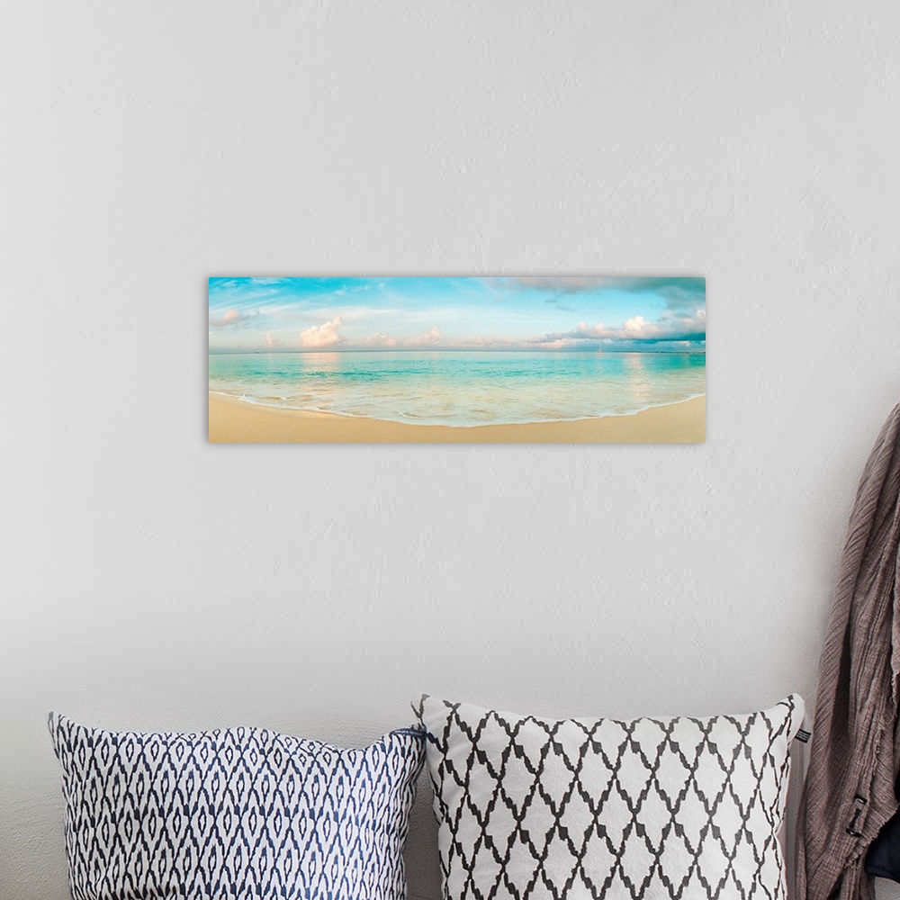 A bohemian room featuring A wide angle panoramic wall hanging of a calm tropical ocean, waves on the beach, and cumulus clo...