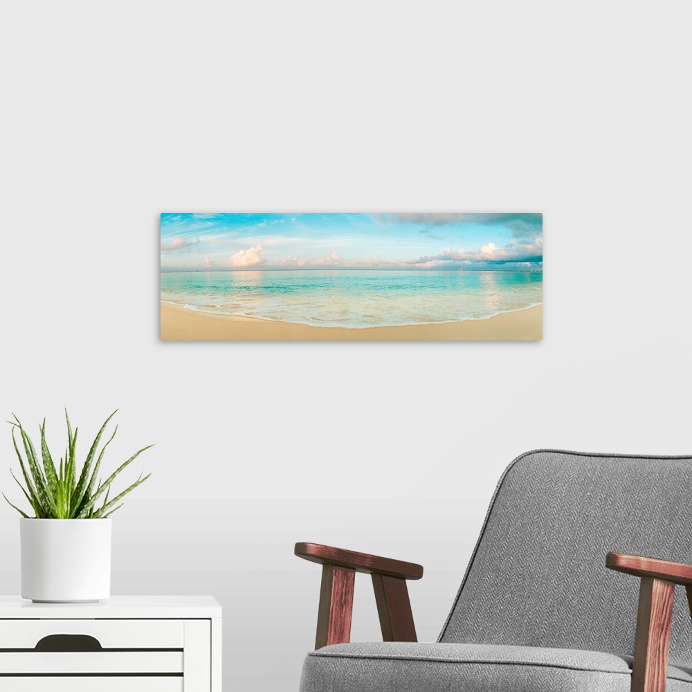 A modern room featuring A wide angle panoramic wall hanging of a calm tropical ocean, waves on the beach, and cumulus clo...