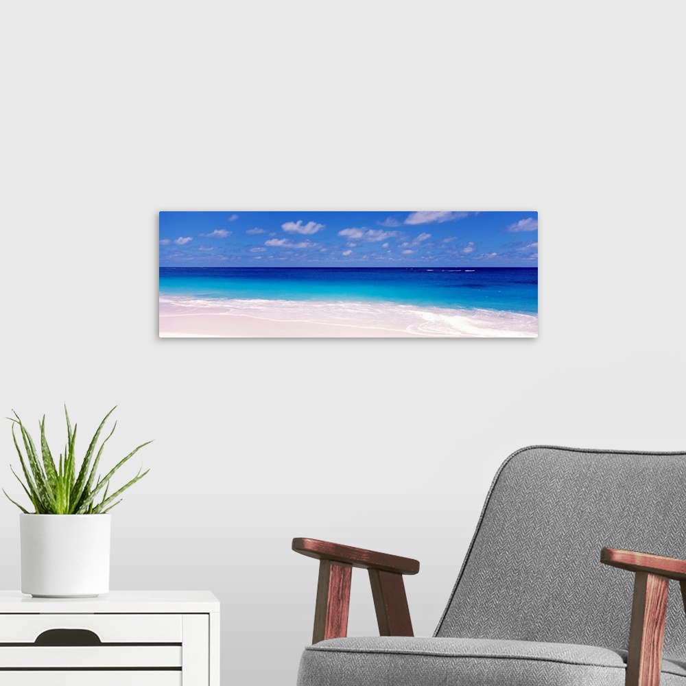 A modern room featuring Oversized wall hanging for the home this is a serene panoramic beach photograph of a calm sea ful...