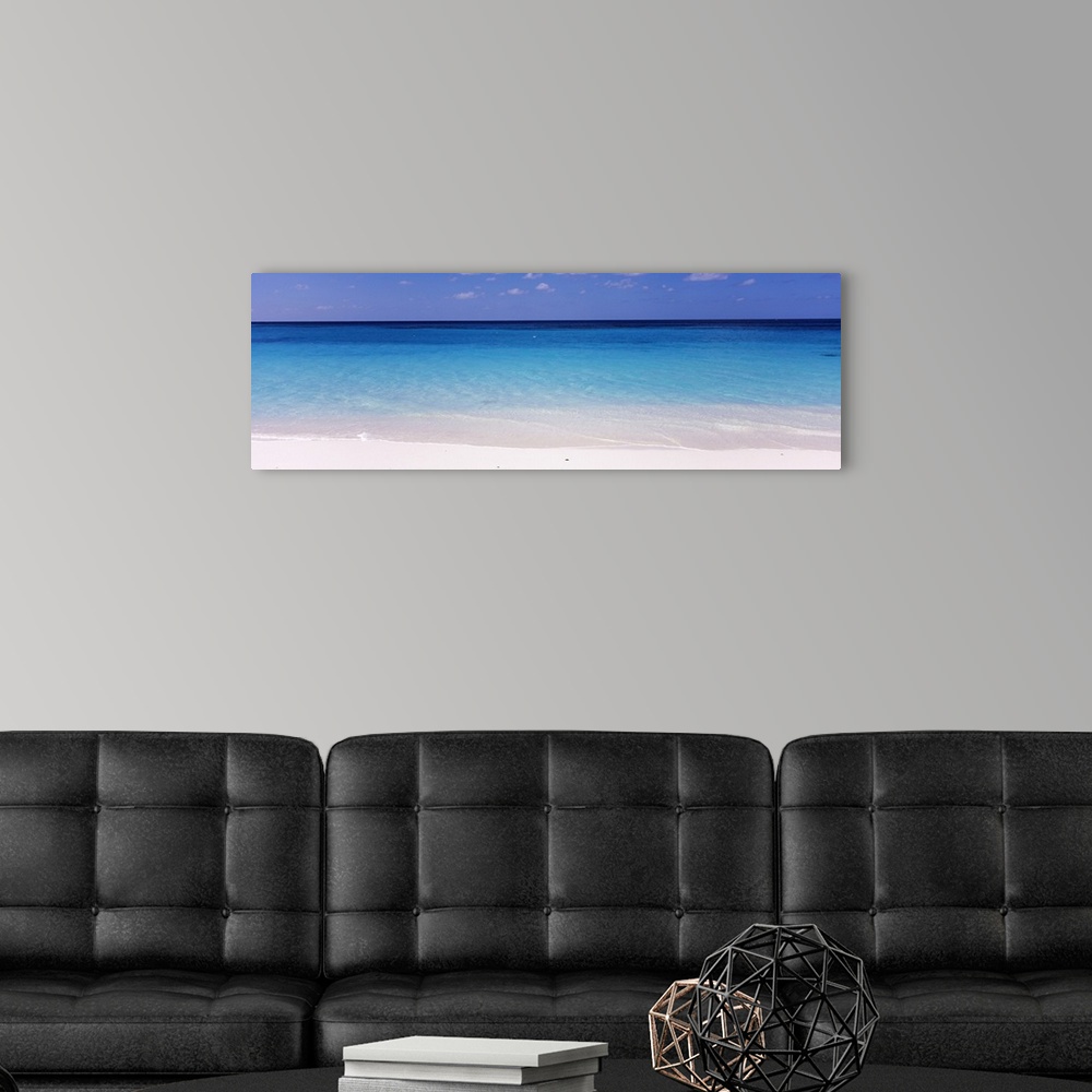 A modern room featuring In this large panoramic photograph crystal clear water trickles onto a white sand beach in Shoal ...