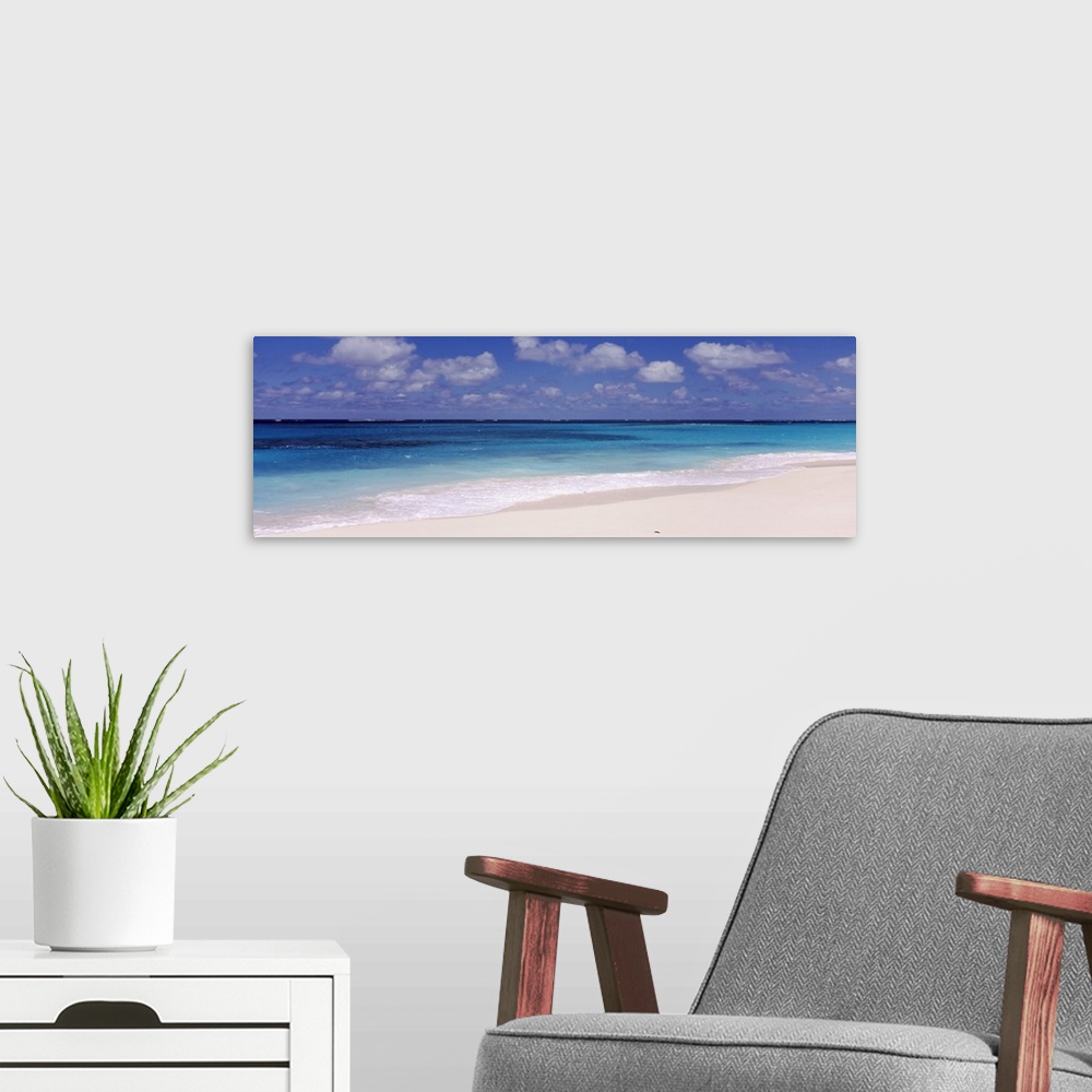 A modern room featuring Panoramic photograph of the ocean against the sand on a cloudy day at Shoal Bay Beach in Anguilla.