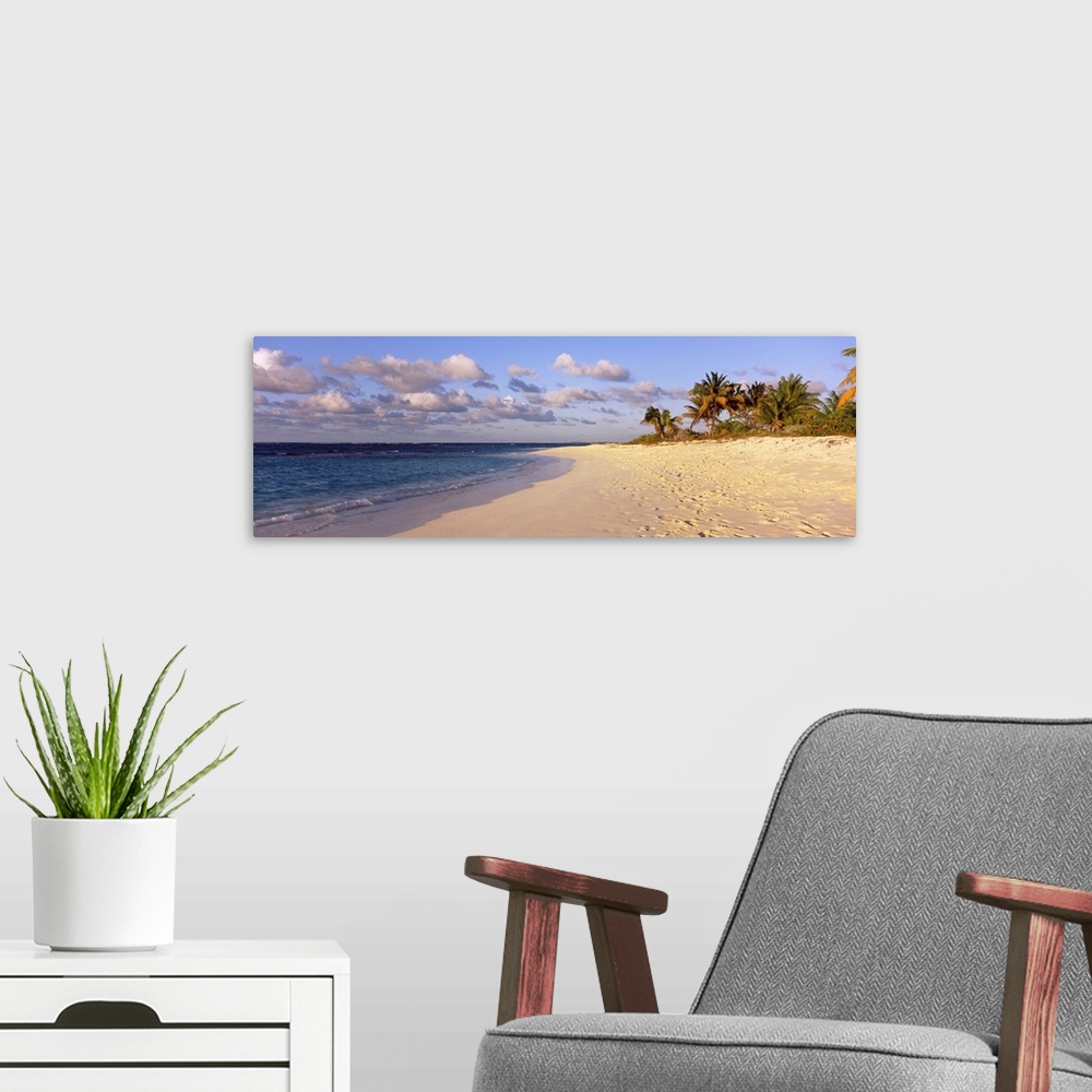 A modern room featuring Big panoramic photo of waves trickling onto the Shoal Bay Beach in Anguilla. Fooprints can be see...