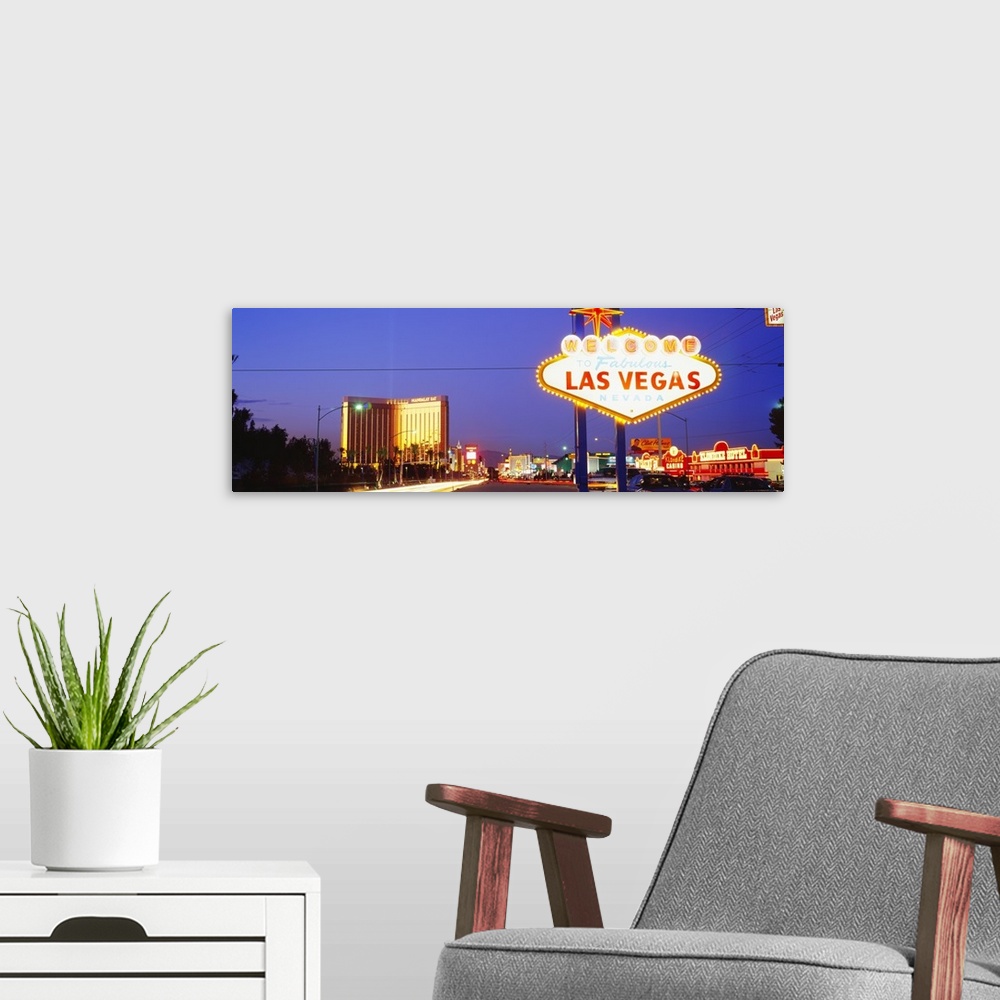 A modern room featuring Panoramic photograph of huge neon sign in ""Sin City"" with buildings lit up in the distance at d...
