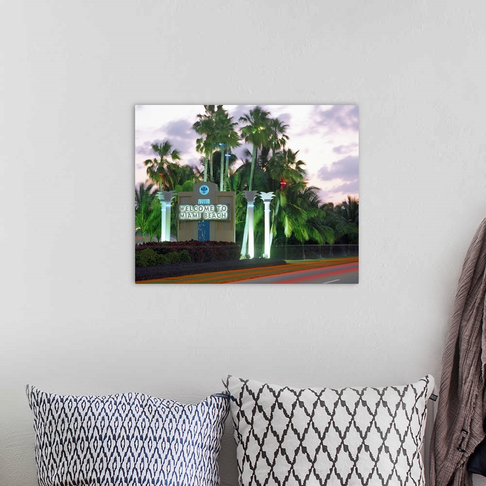 A bohemian room featuring This is a road size sign illuminated by neon lights and surrounded by palm trees and photographed...