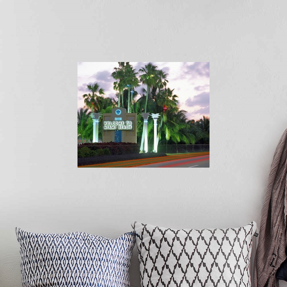 A bohemian room featuring This is a road size sign illuminated by neon lights and surrounded by palm trees and photographed...