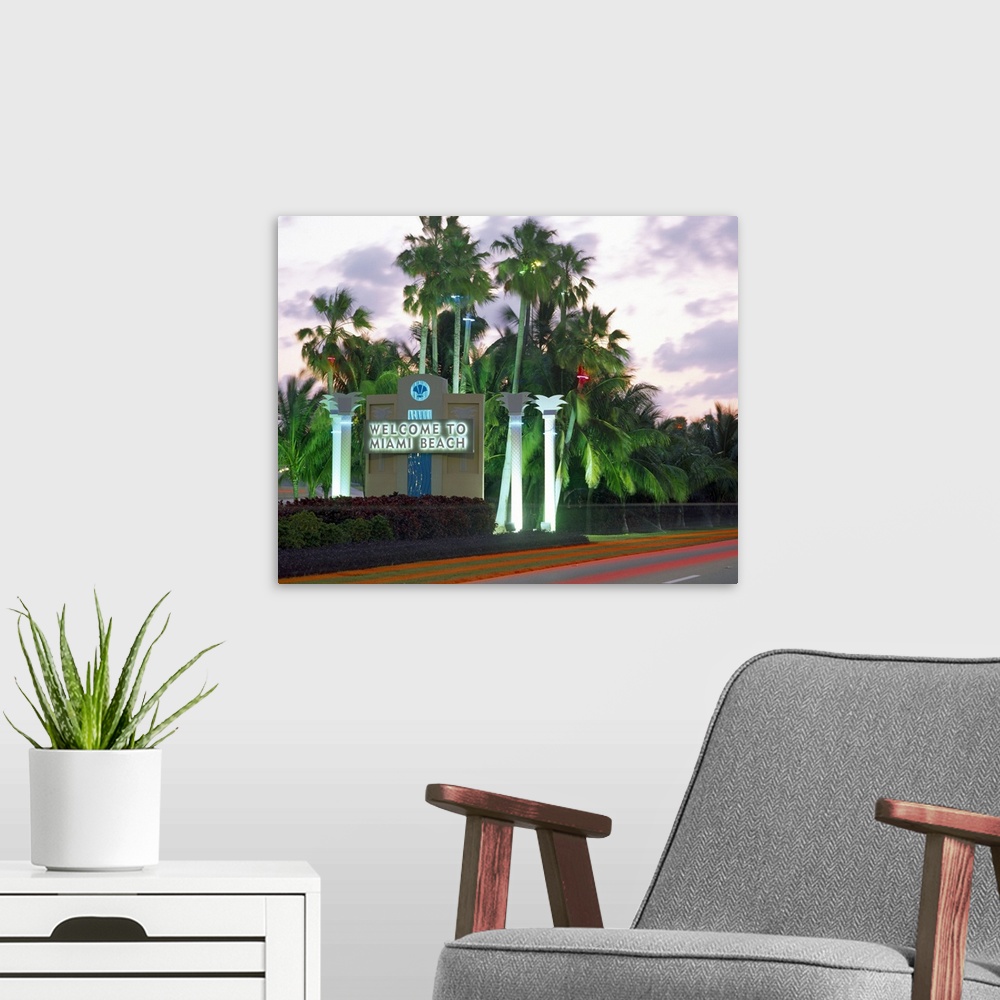 A modern room featuring This is a road size sign illuminated by neon lights and surrounded by palm trees and photographed...