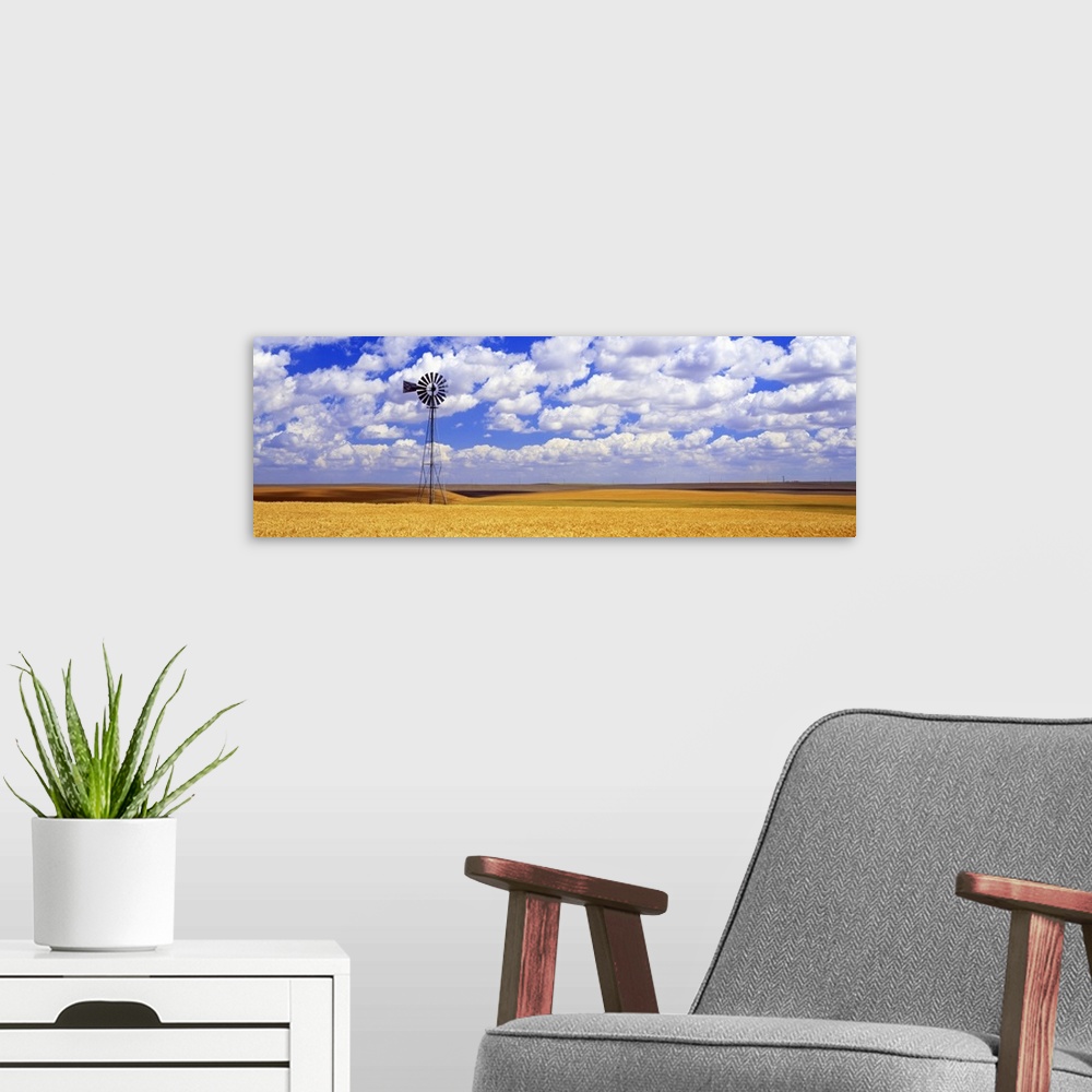 A modern room featuring Panoramic photograph of field with tall windmill under a cloudy sky.