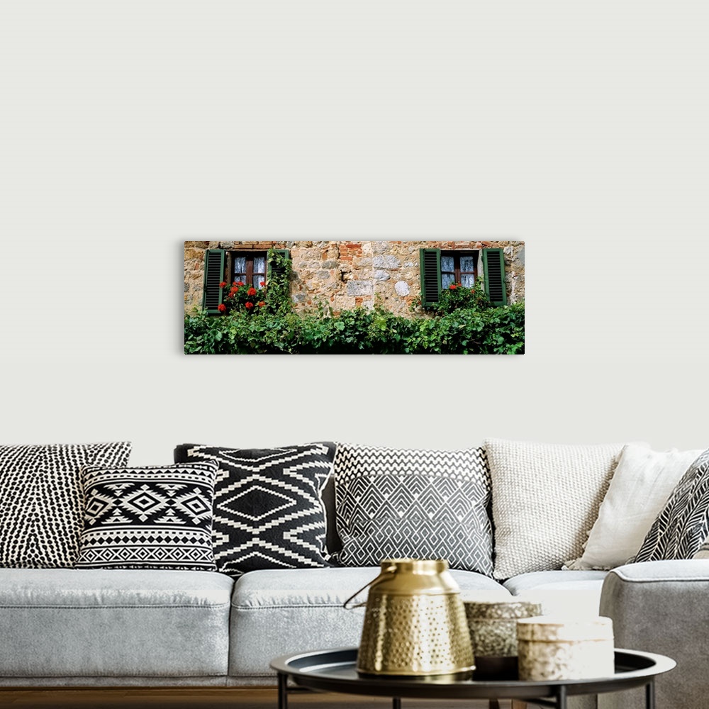 A bohemian room featuring Rustic masonry makes the wall of a house surrounded by overgrown hedges and enormous red flowers ...