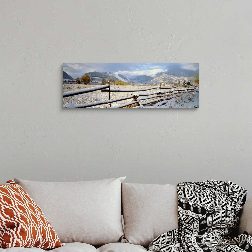 A bohemian room featuring Panoramic photo of a snow covered landscape with a thin wooden fence running through it in the fo...