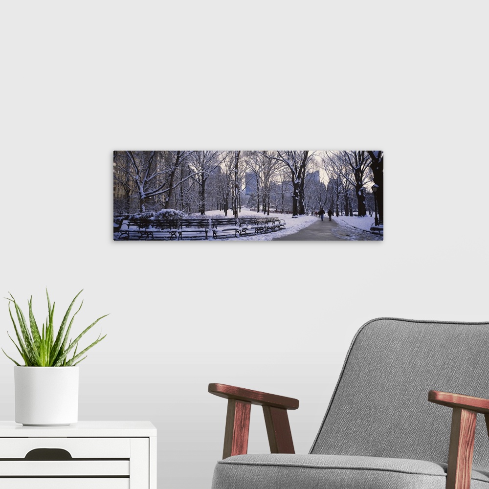 A modern room featuring Big, landscape photograph of New York's Central Park in the snow with downtown Manhattan in the b...