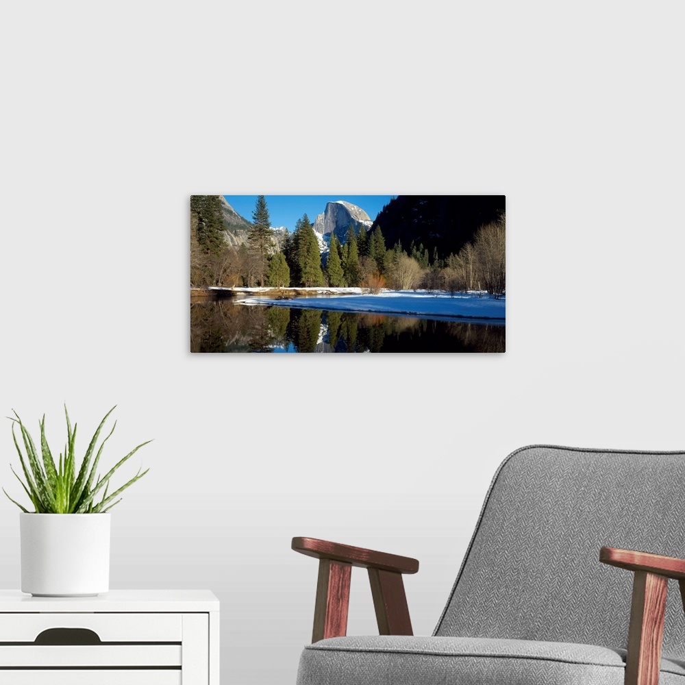 A modern room featuring This picture is taken of Yosemite during winter with trees lining the water and a view of a mount...