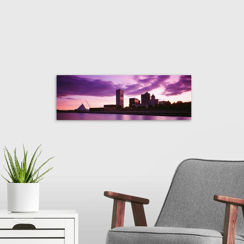 A modern room featuring Taken from on the water at sunset this panoramic photograph shows city skyscrapers built along th...
