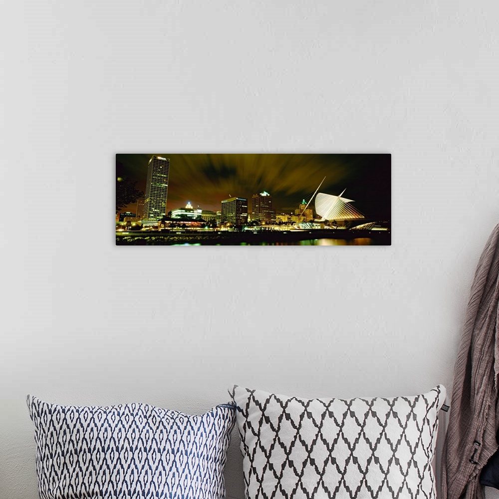 A bohemian room featuring Wide angle photograph from water level of skyline lit up on panoramic wall art.